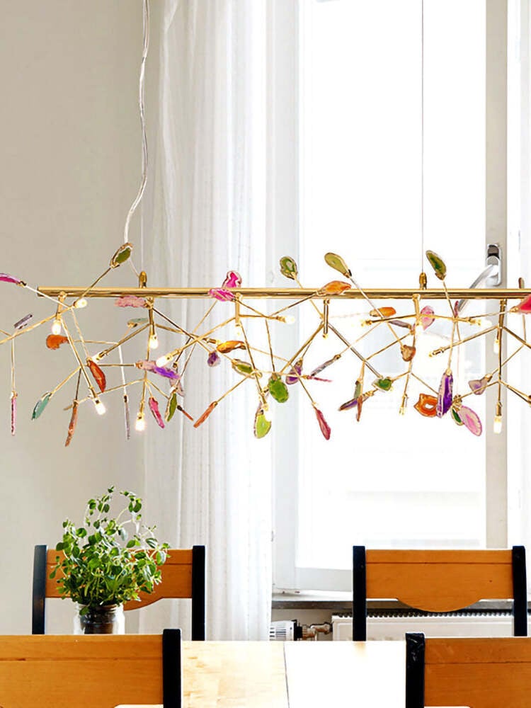 Linear stone-slice chandelier in front of tall windows