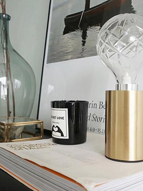 Cropped clear globe lamp beside candle and framed art