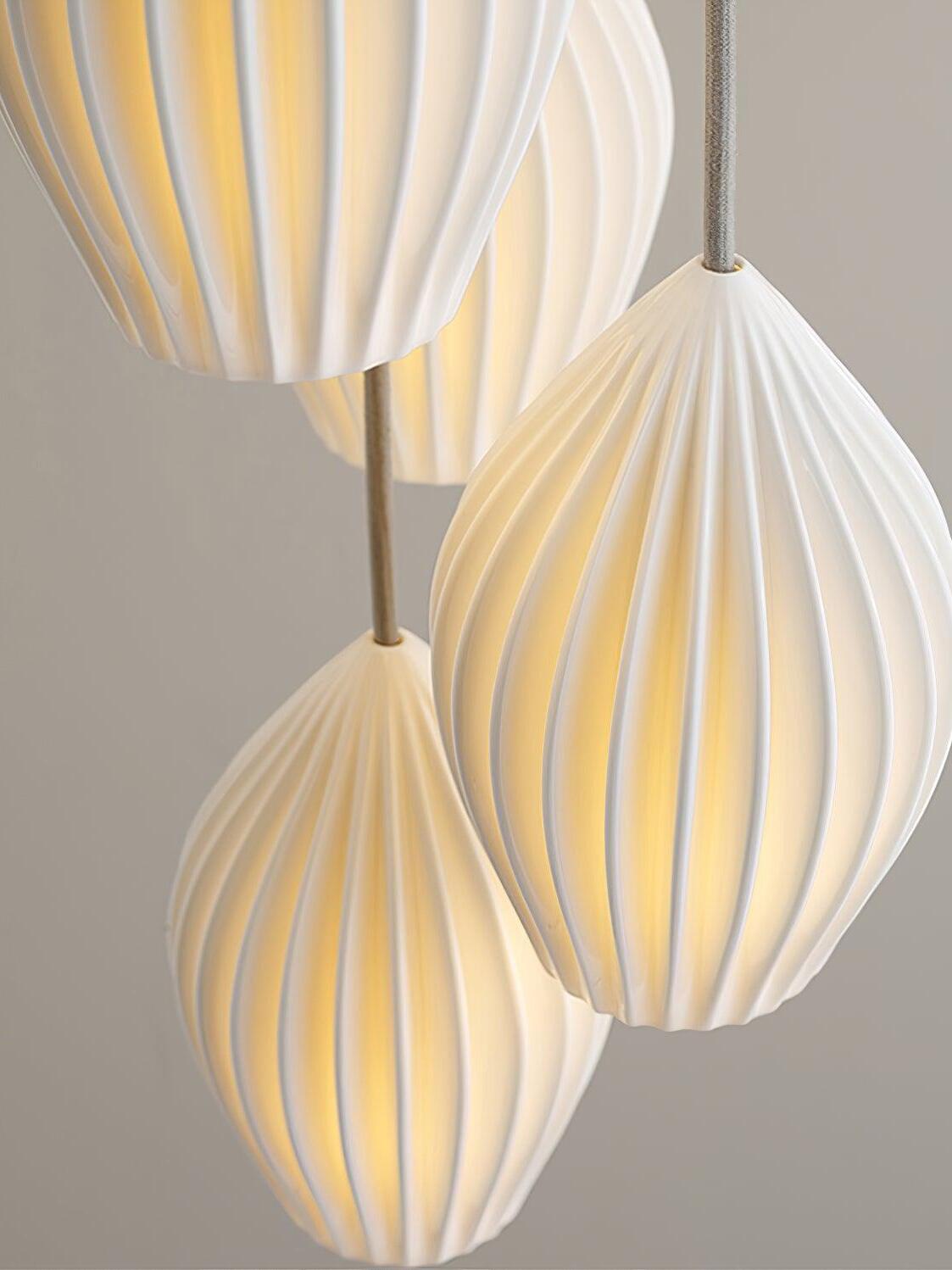 Three illuminated white ribbed ceramic shades hanging at staggered heights