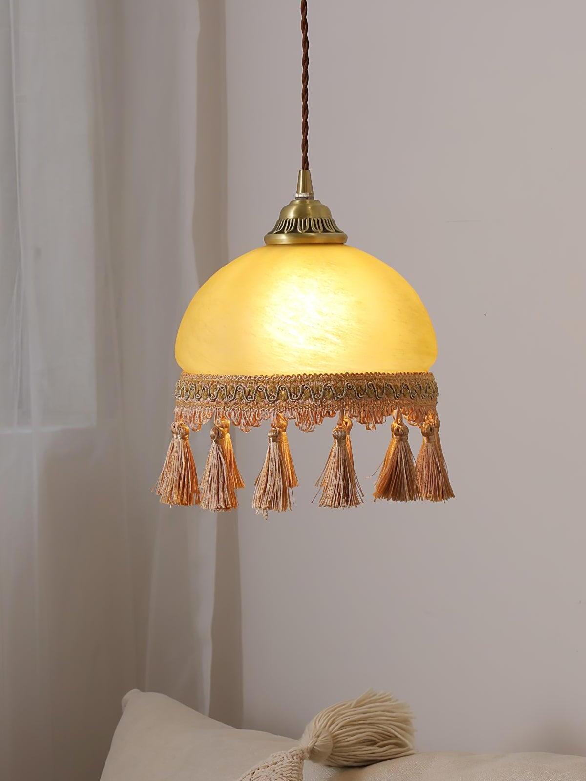 Glowing yellow pendant and brown tassels before curtain