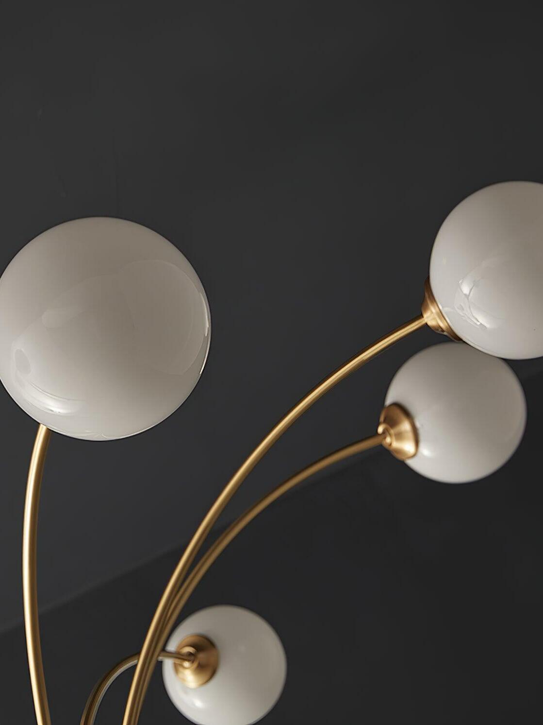 Close view of smooth white globes and round collars on curved brass-tone arms against a dark background