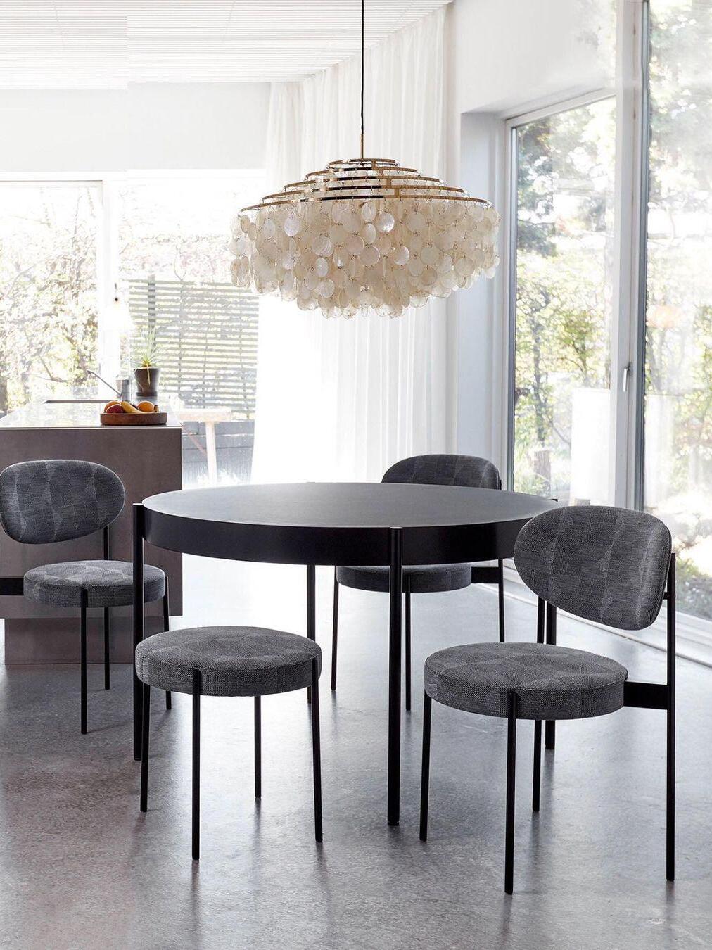 Round white shell fixture above a dark dining table