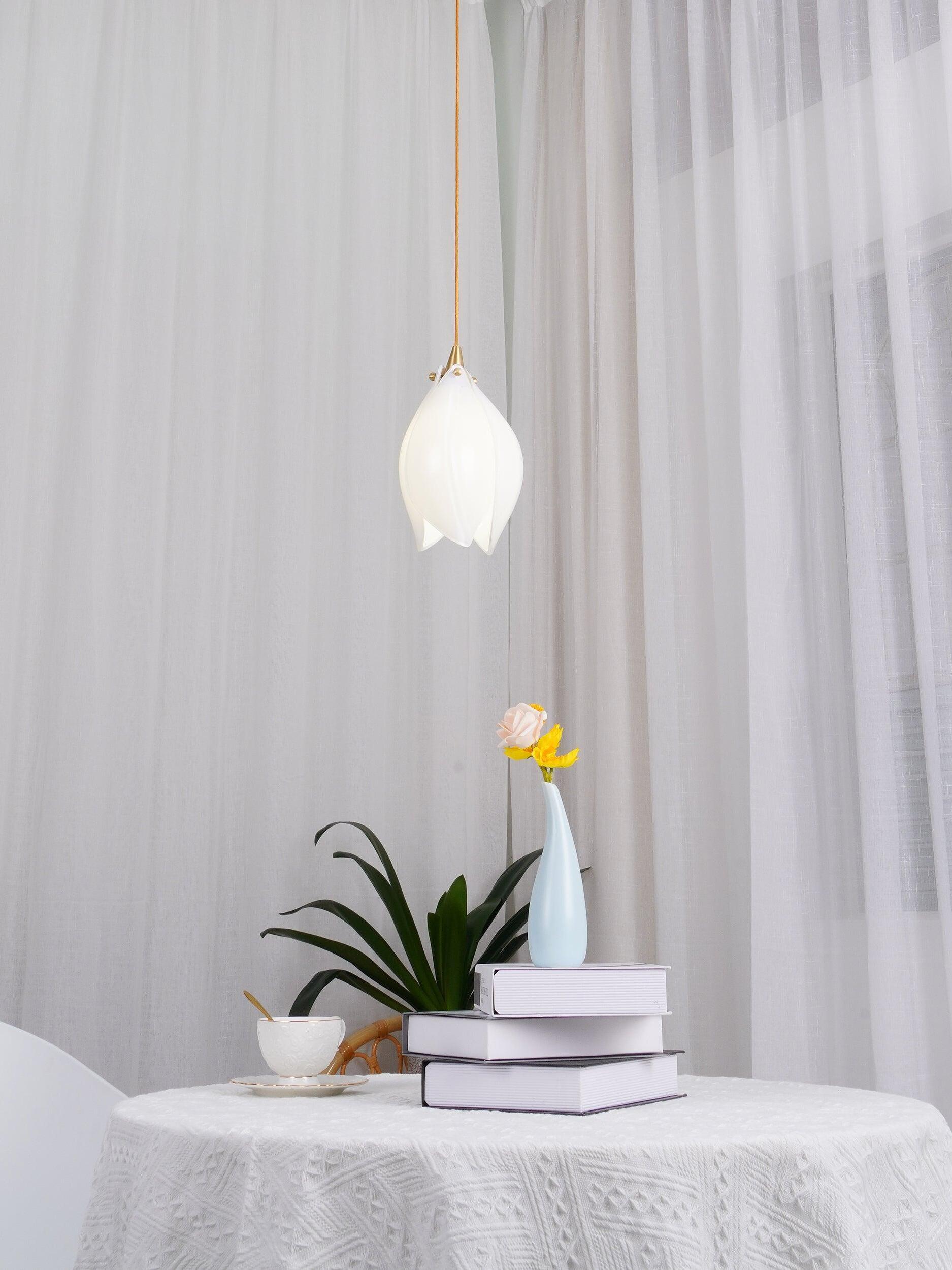 Single bud pendant above a flower and books