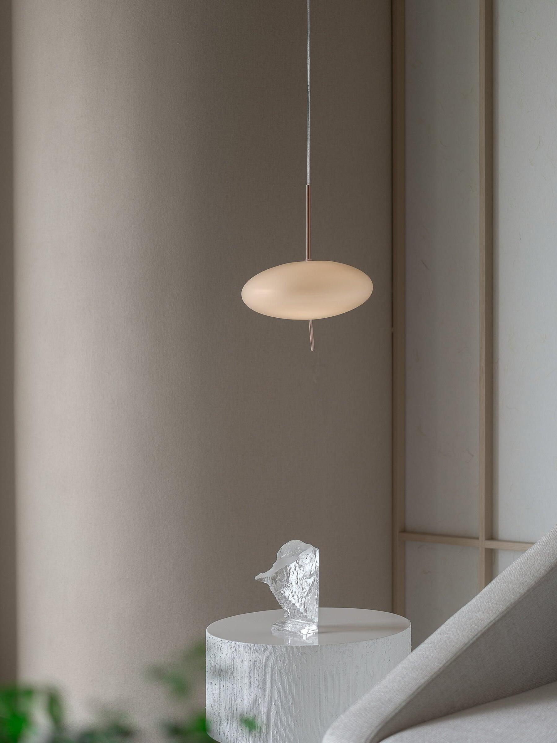 A small white pendant beside a pale lounge chair and a side table with a tissue box
