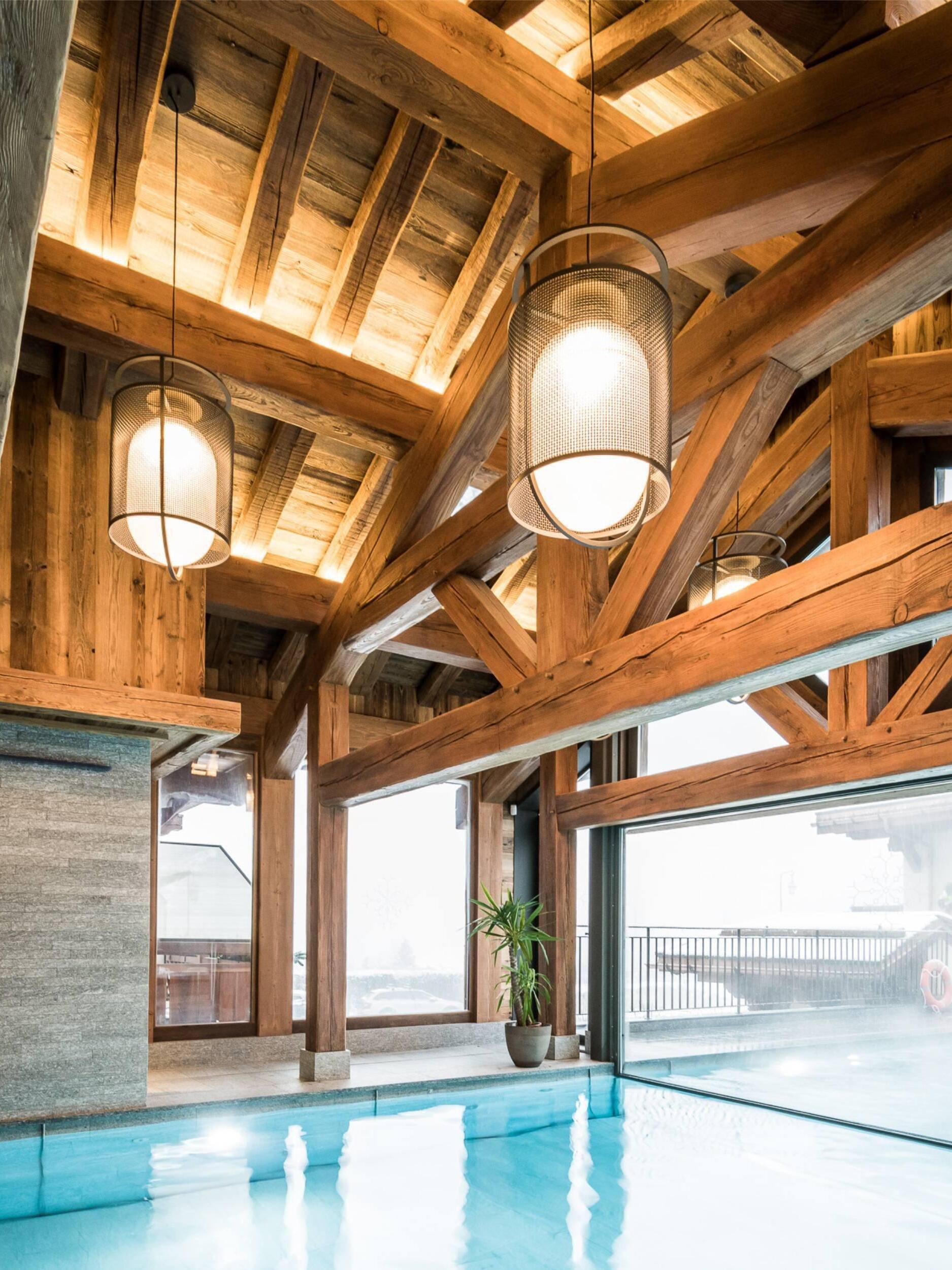 Several black lantern pendants beneath timber roof by a pool