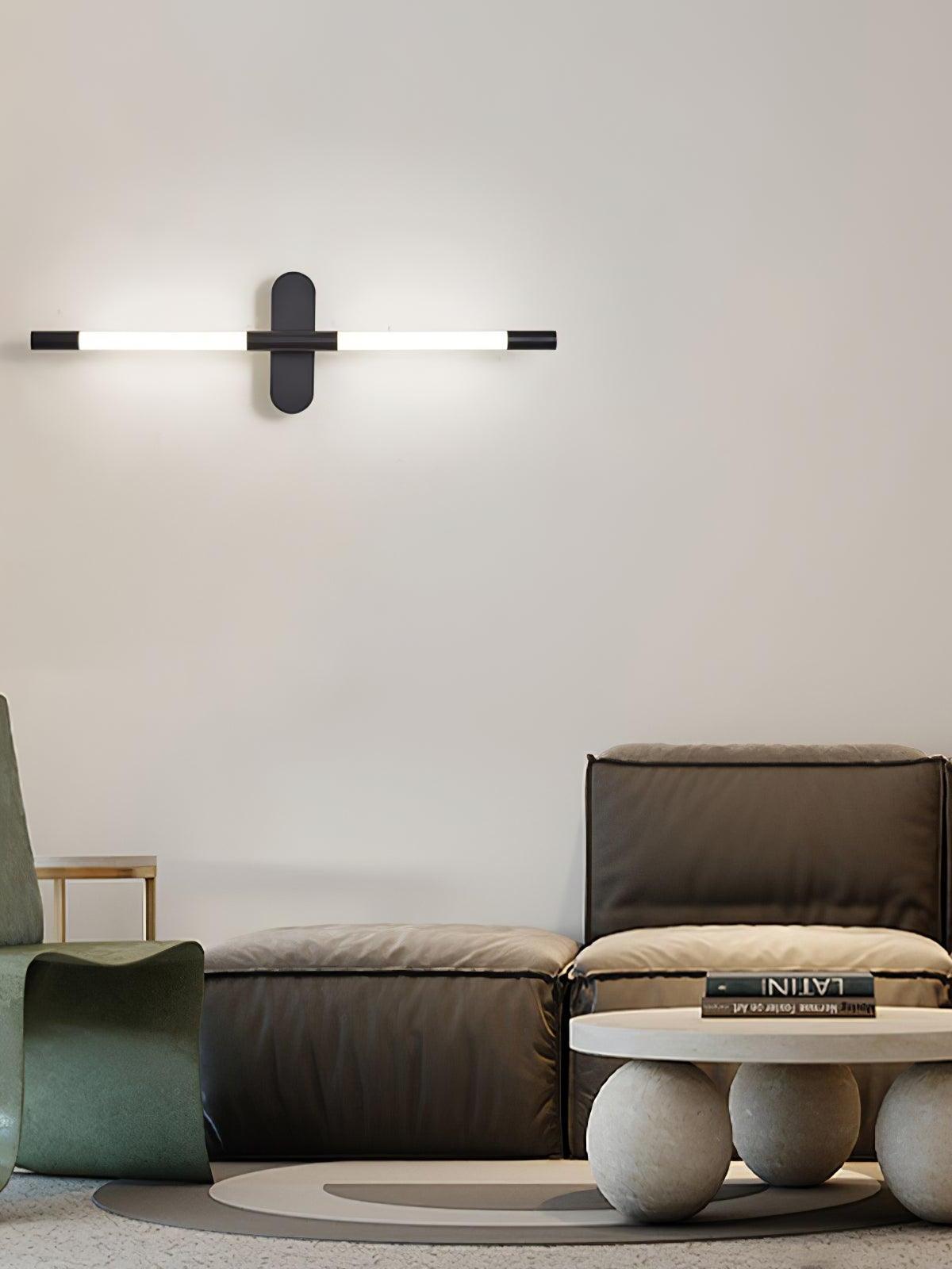 Horizontal black Agnes wall light above a chair, ottoman and low table