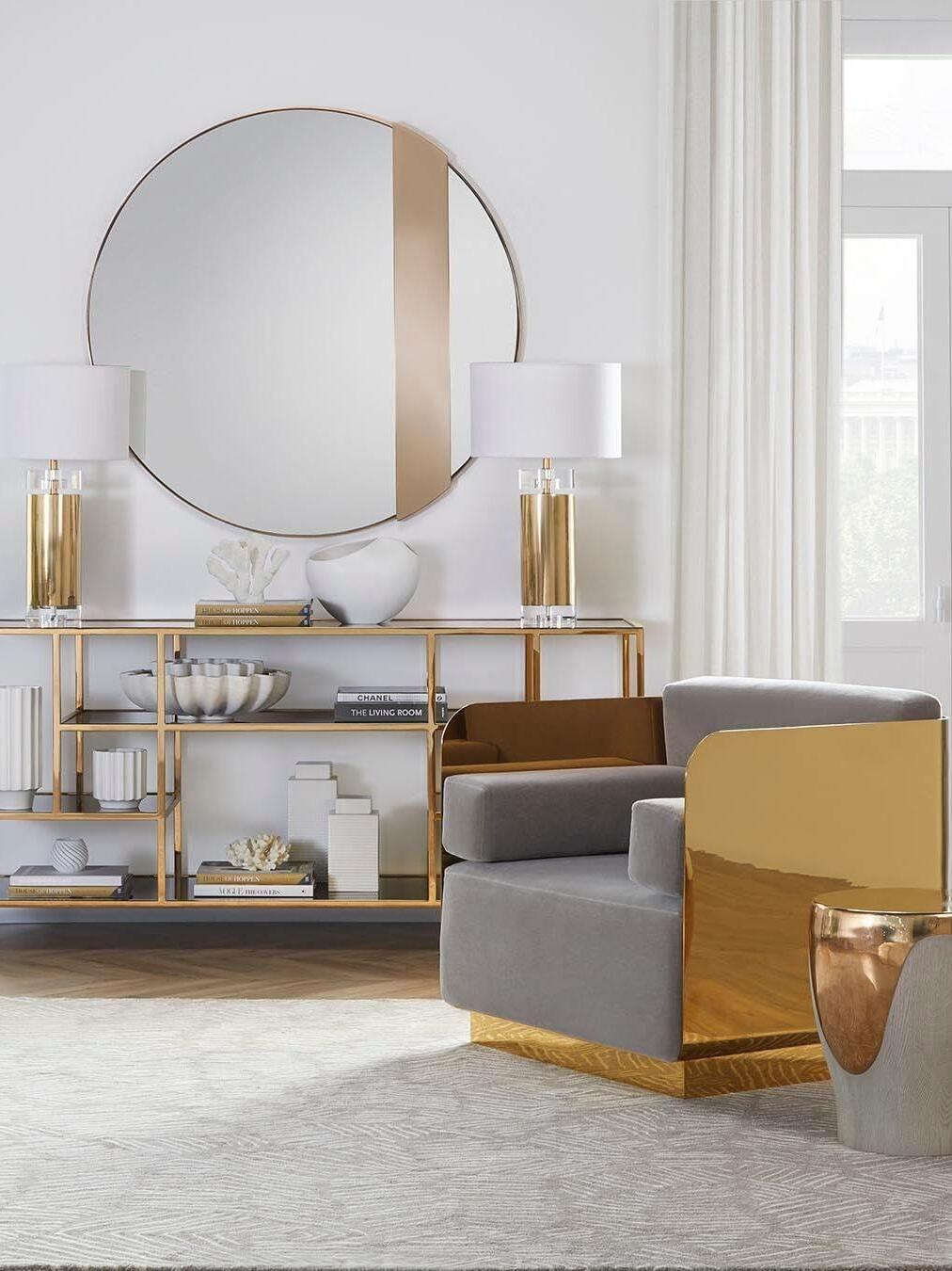 Wide seating room with paired console lamps, round mirror and upholstered chair