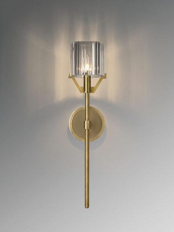 Lit Gold wall sconce with a faceted cylindrical shade
