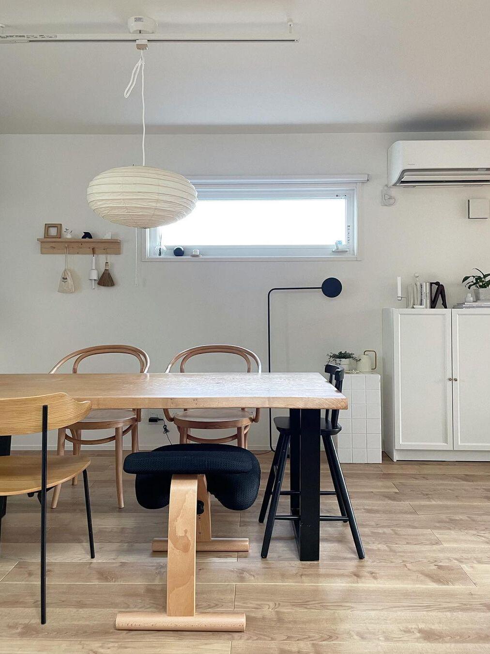 Front dining view with pale paper lantern and white cord under a ceiling track, above a long table and mixed chairs