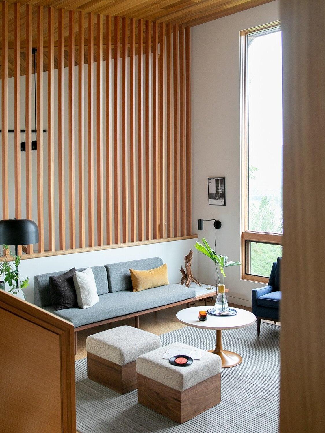 Black cylindrical wall light near sofa and wooden slatted divider
