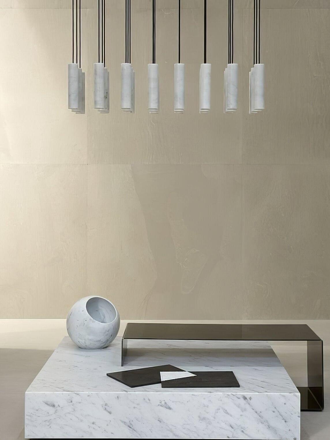 A row of white Silo pendants above a pale low table with books and a curved sculptural object