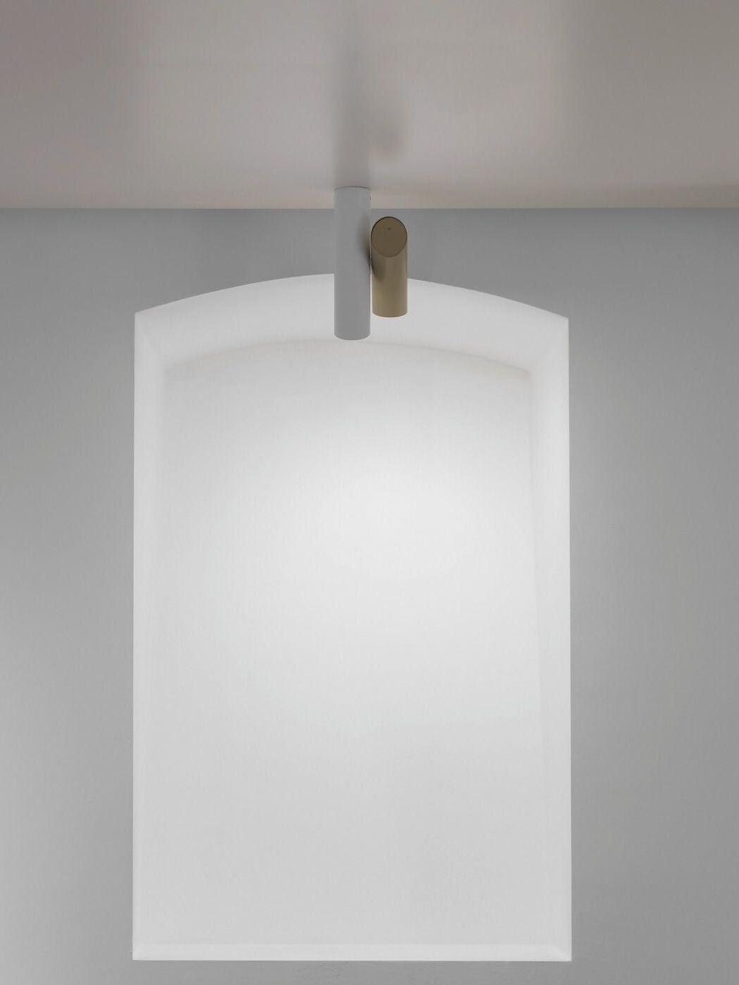 White and gold-tone Tubes light above an arched recessed wall panel