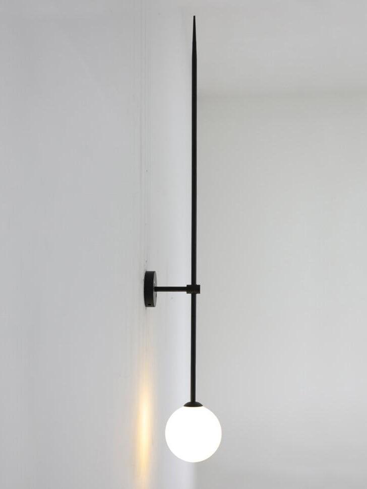 Lit black rod wall light in side view, with a white globe at the lower end