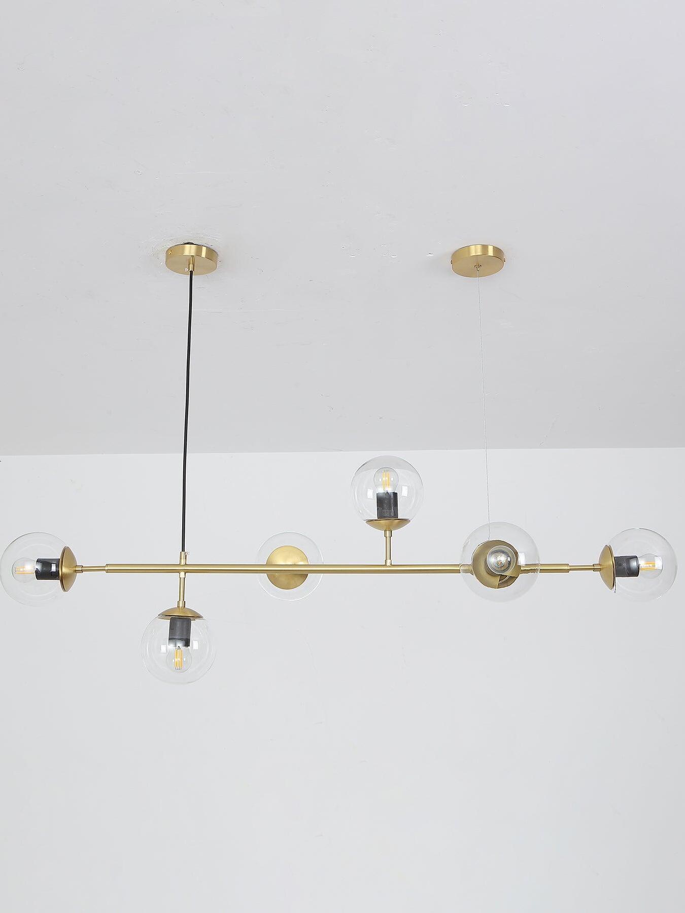 Clear-globe linear chandelier below a pale ceiling