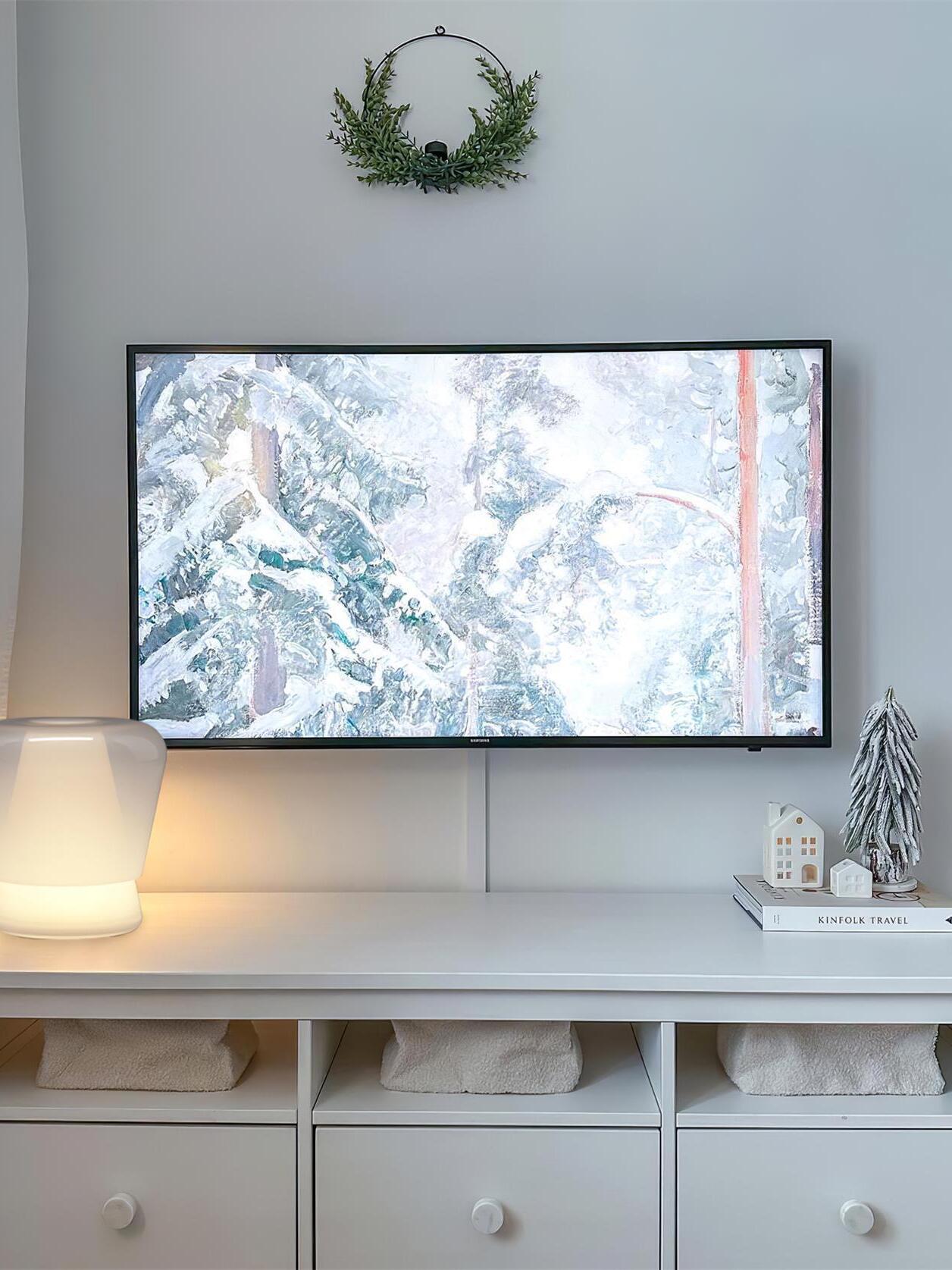 White Jumelle lamp on low cabinet beneath television