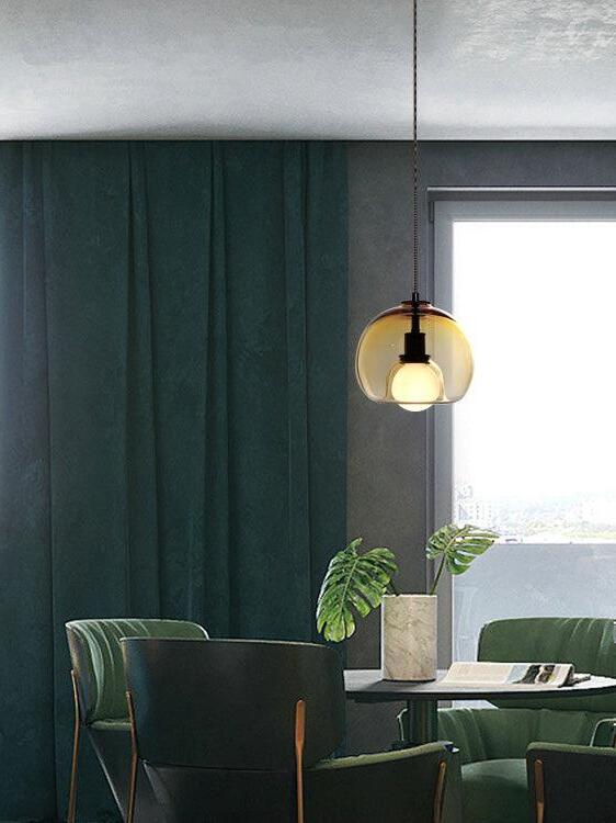 Warm-toned Eres pendant with a globe bulb beside dark green wall panels.