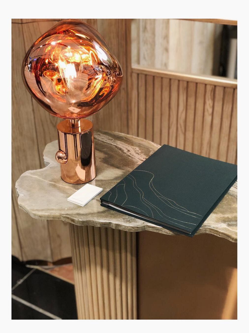 Reflective Melt lamp on a side table beside books