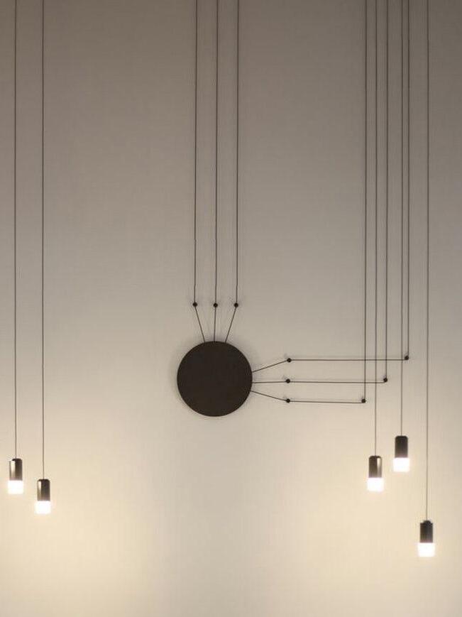 Six lit black heads and cables routed from a round wall plate to the ceiling