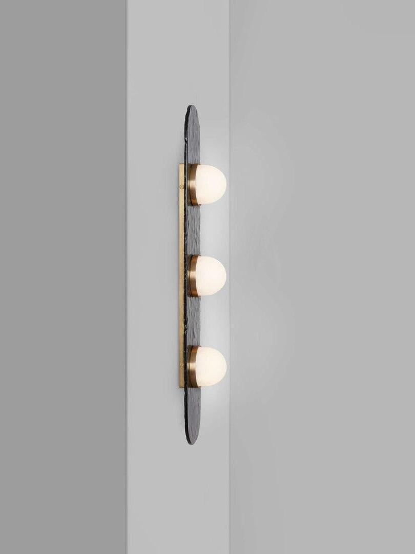 Three-light Modulo mounted on a pale wall, viewed from the side