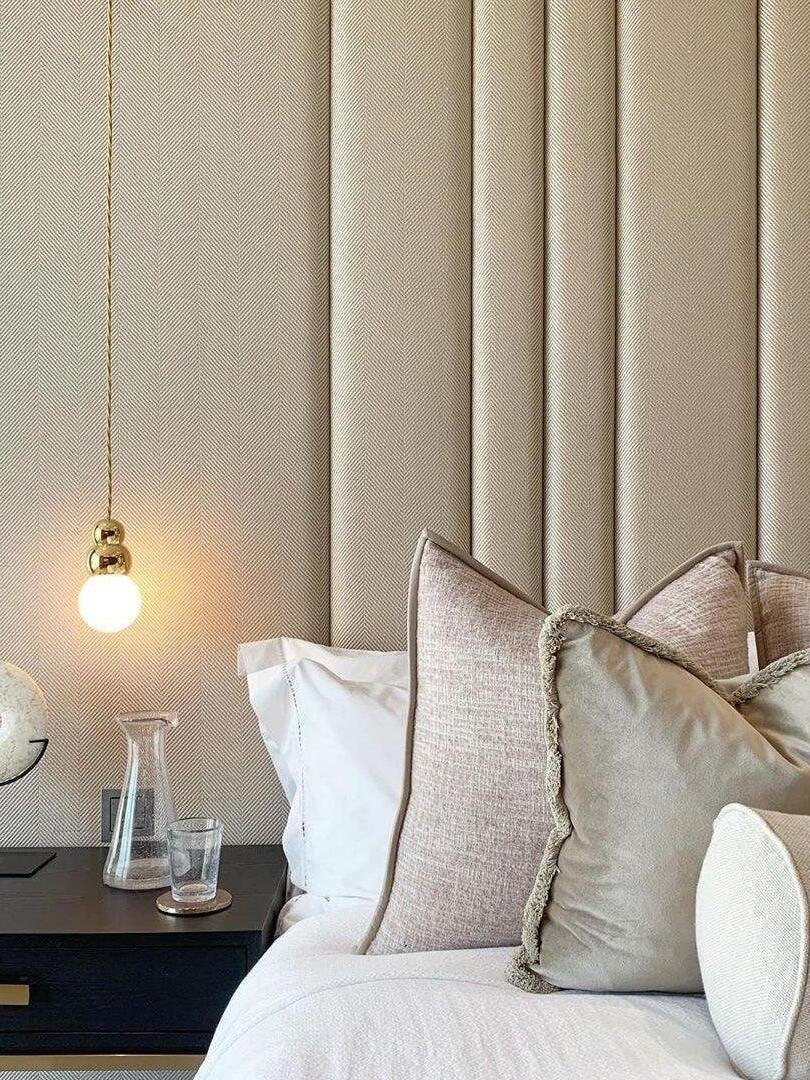 Small gold hanging wall light beside a bed