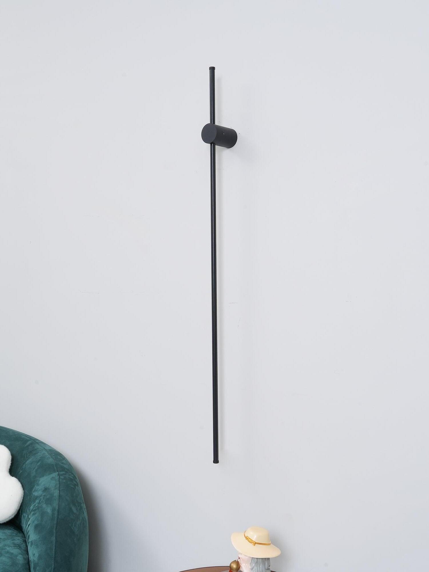 Unlit black rod and cylindrical mount on a pale wall