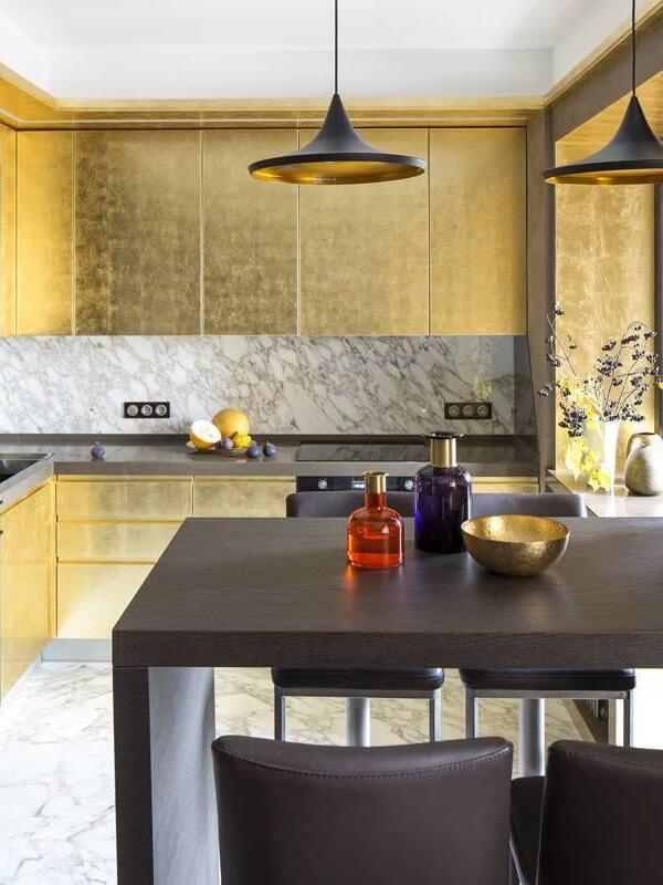 Wide black pendants in a gold-toned kitchen