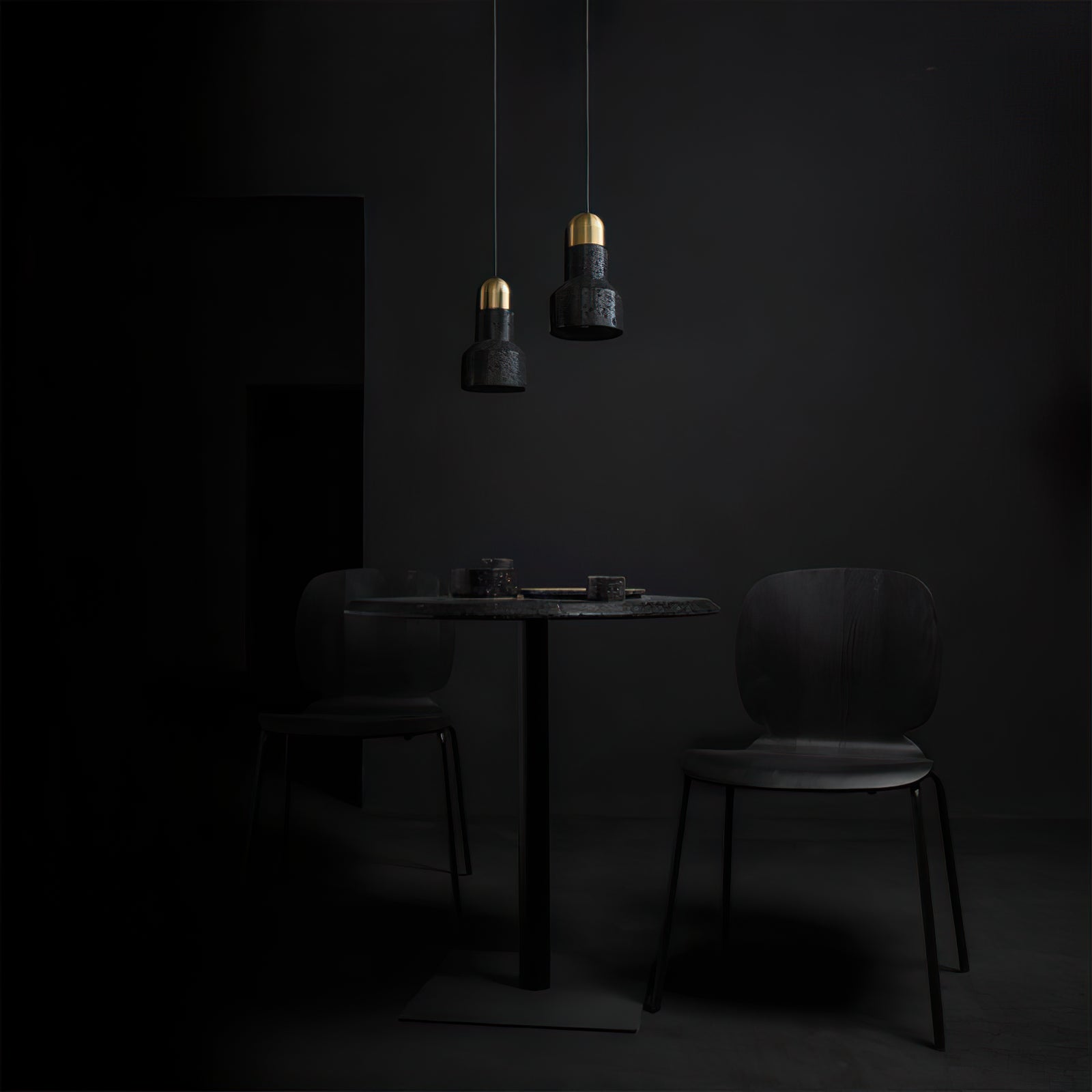 Two small black stone pendants above a dark dining table