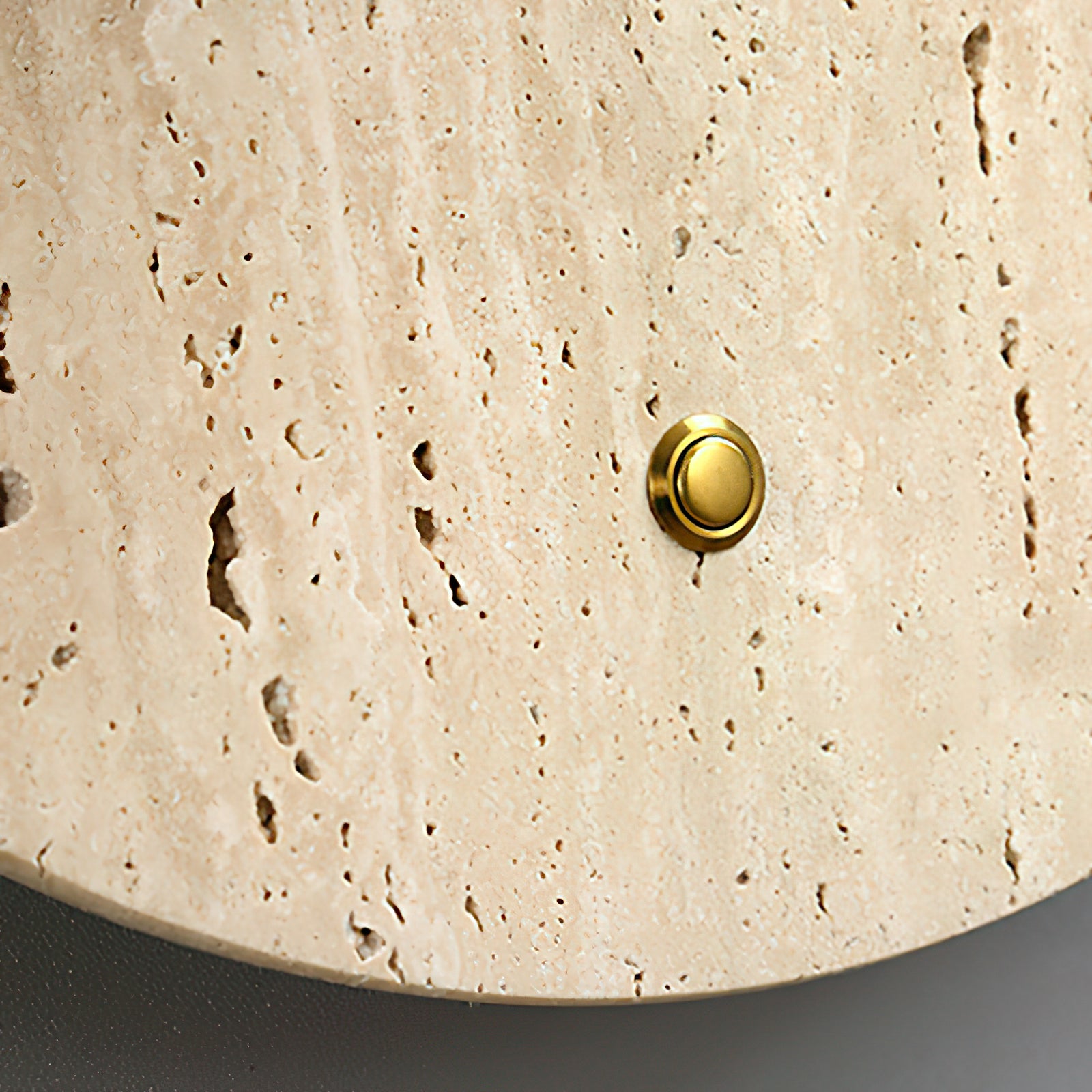Close-up of natural stone pores and a round brass-colored detail