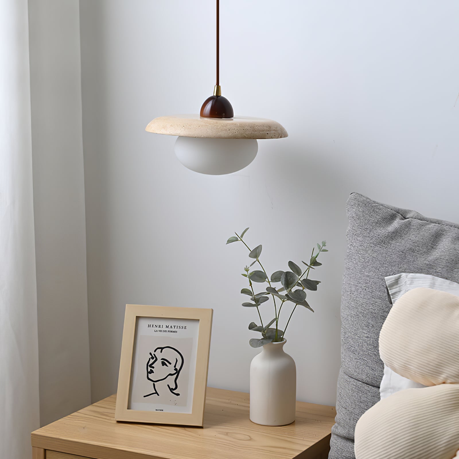 Unlit travertine pendant shown next to a bed