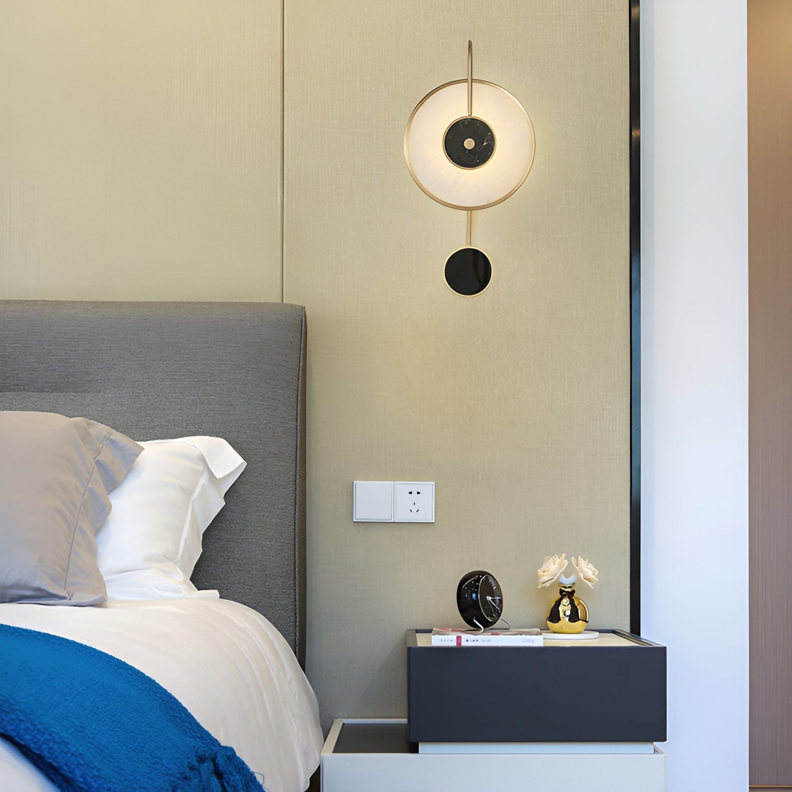 Black-and-white geometric wall lamp above a bedside table