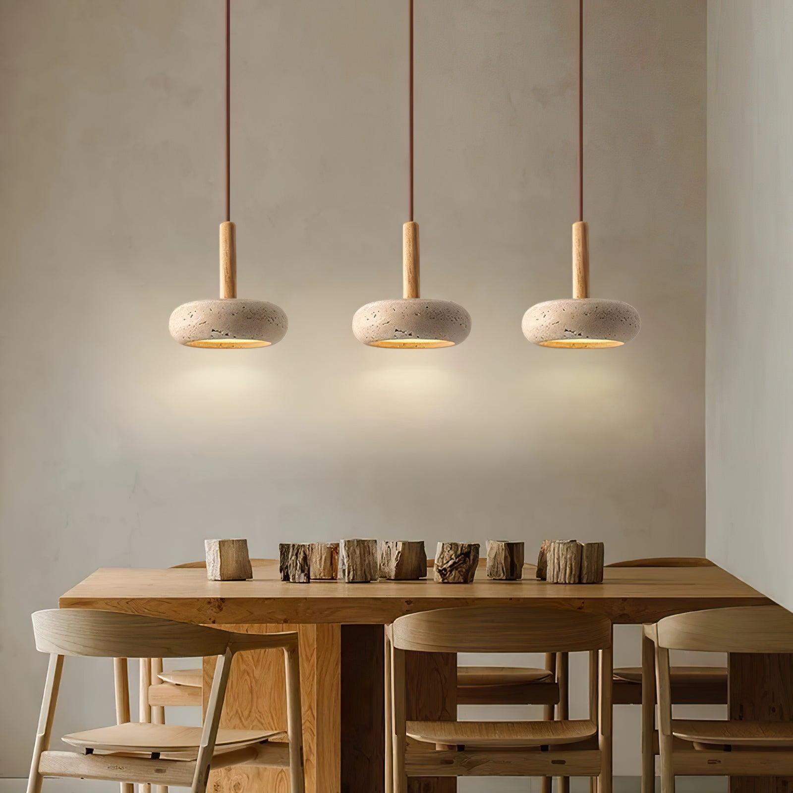 Three rounded stone pendants above a wooden dining table
