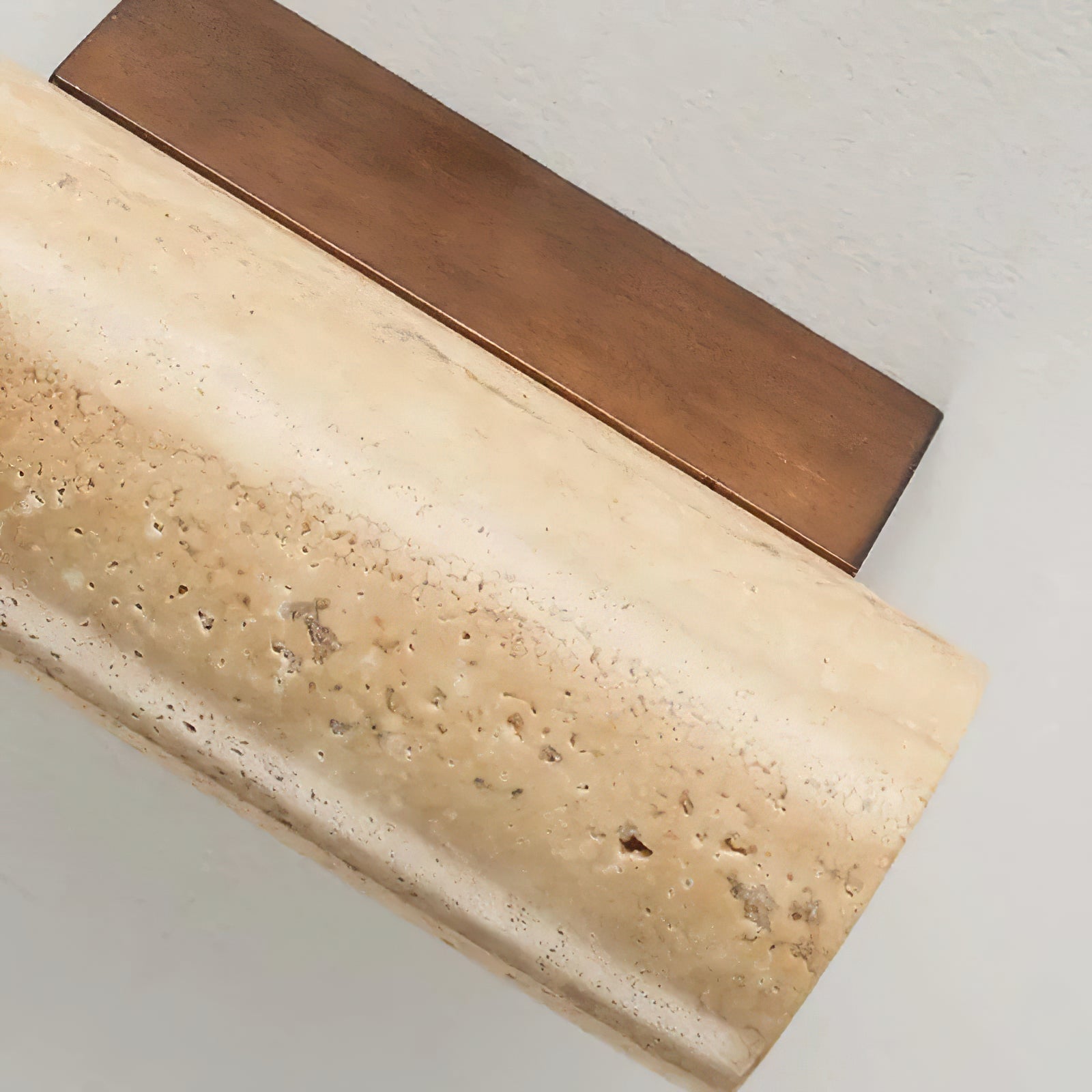 Angled detail of travertine texture and brown wooden backplate