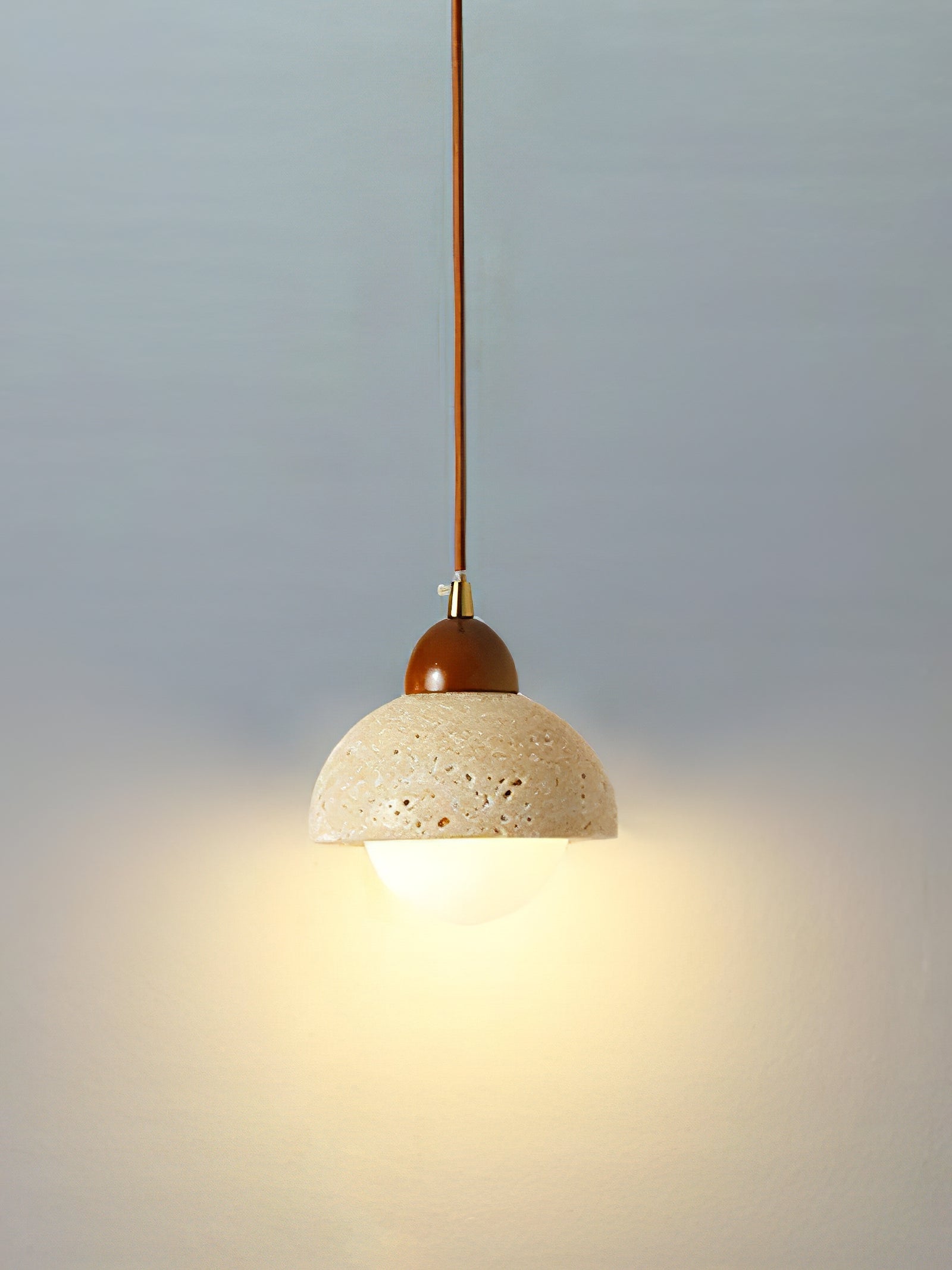 Small illuminated travertine dome pendant against a plain wall