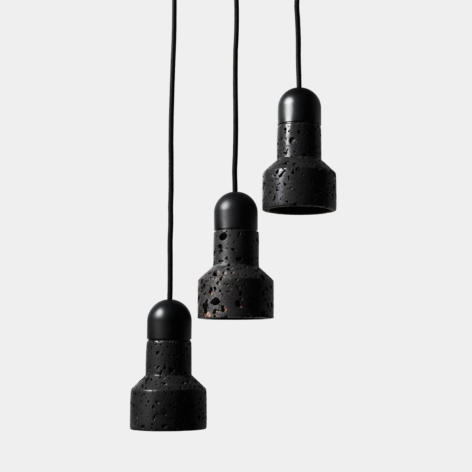 Three all-black textured pendants suspended at staggered heights