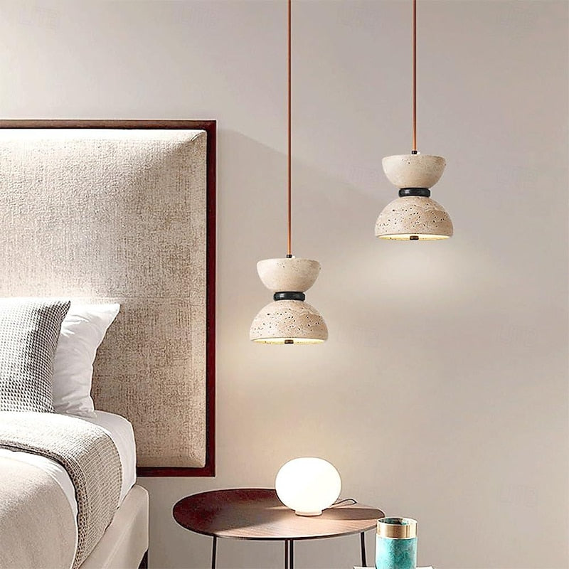 Small travertine pendant beside a bed and framed artwork