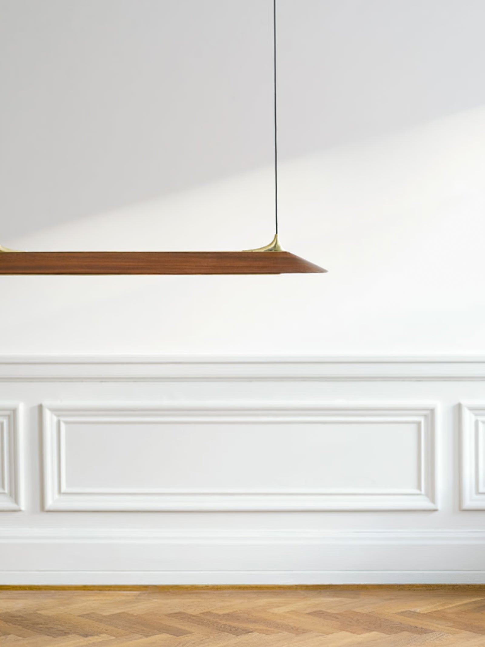 Brown linear pendant against a white panelled wall