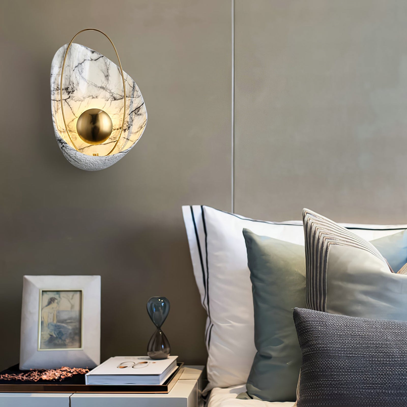Shell-shaped wall lamp beside a grey upholstered headboard
