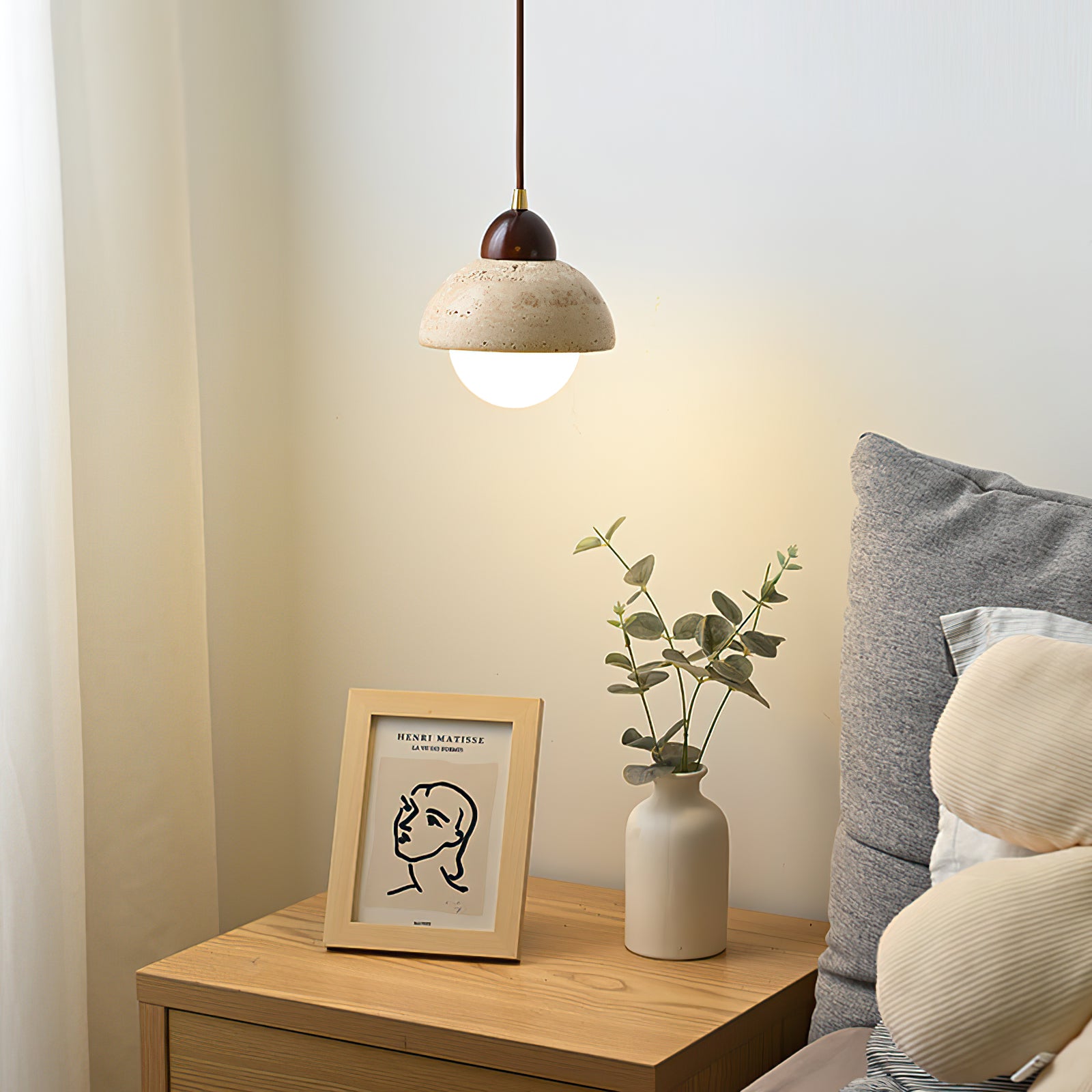 Lit stone dome pendant over a wooden bedside table
