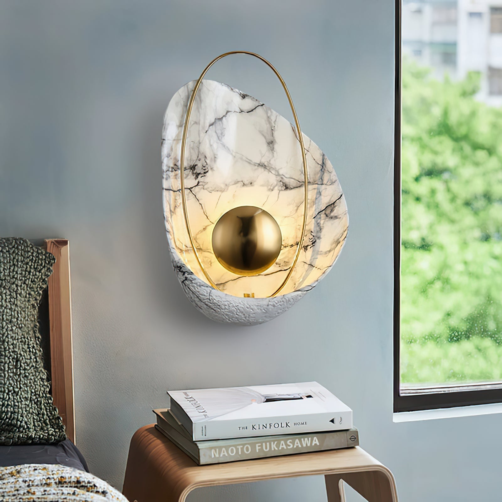 Veined shell wall light above a bedside table and books