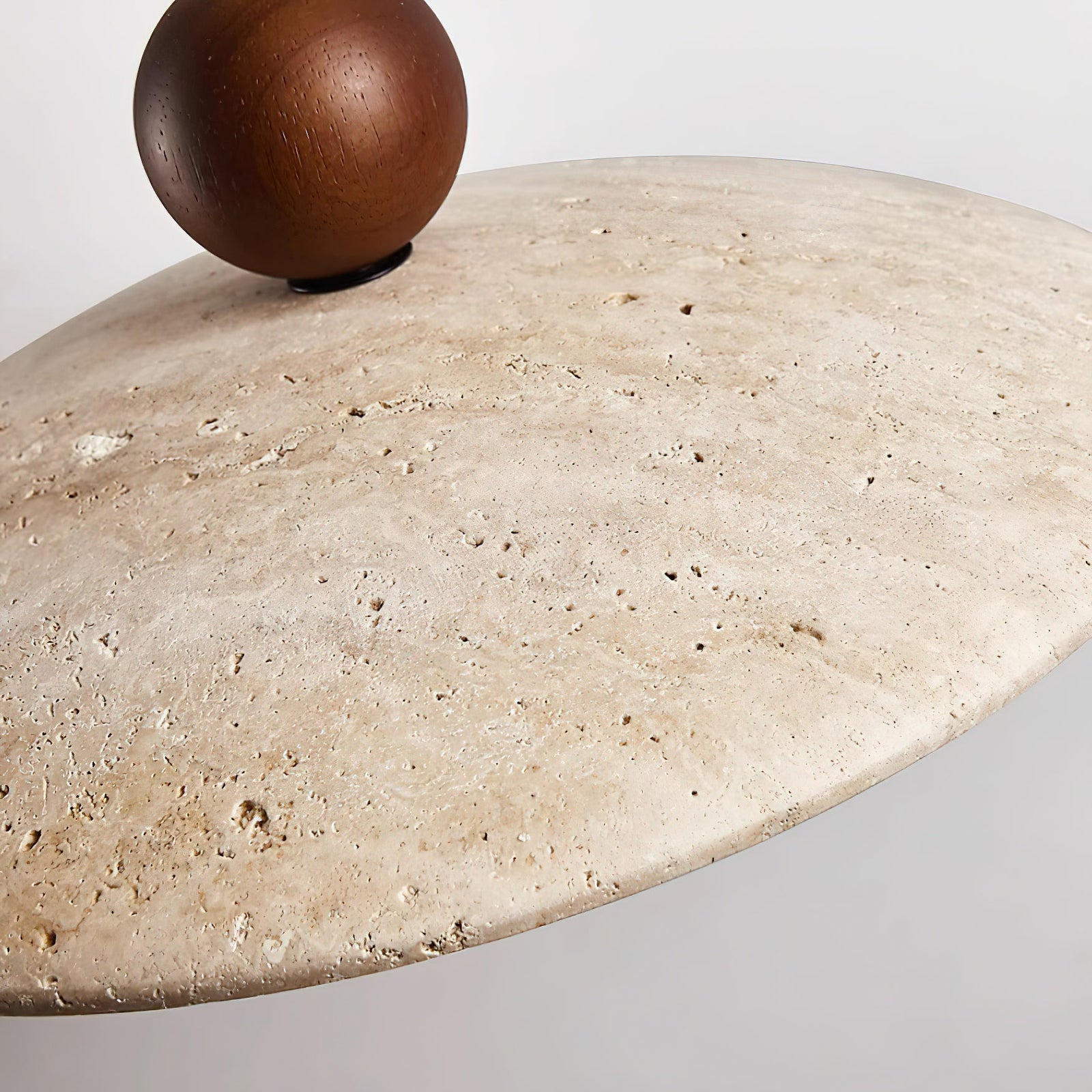 Close-up of textured stone disc and dark wooden sphere