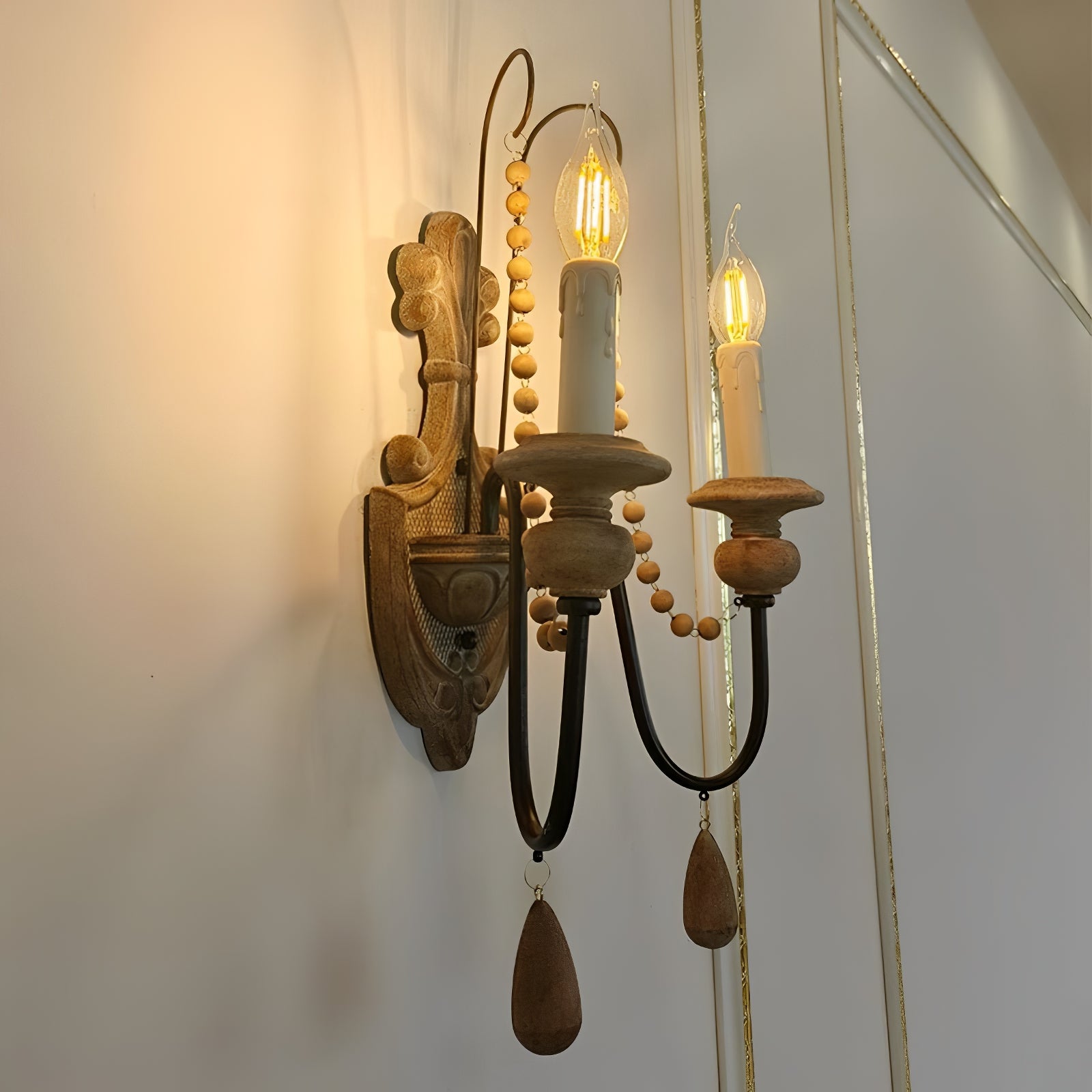 Angled view of the double-arm wall sconce showing its wood backplate and candle holders