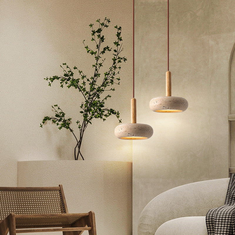 Two travertine pendants at different heights beside seating