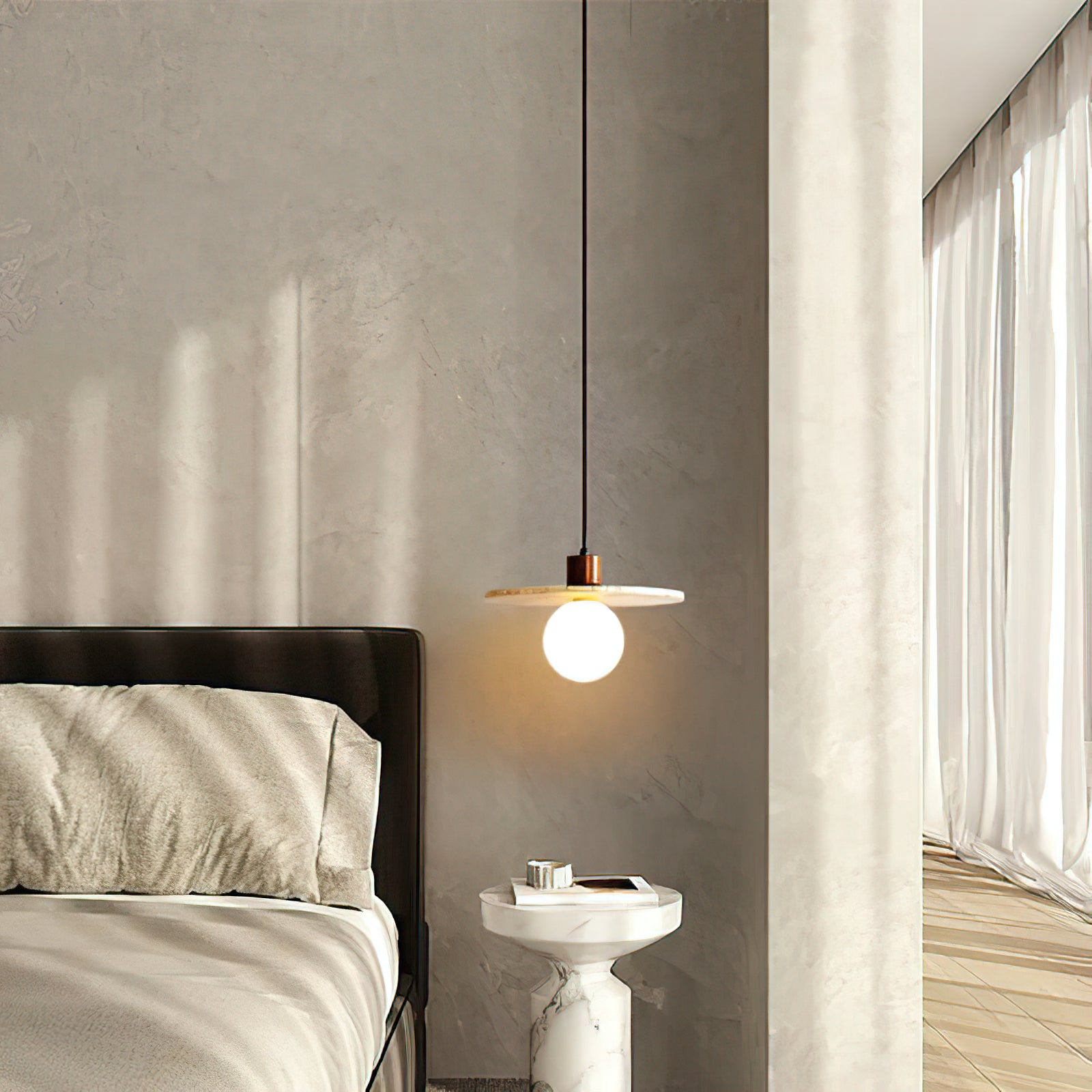 Travertine disc pendant beside a bed and small side table