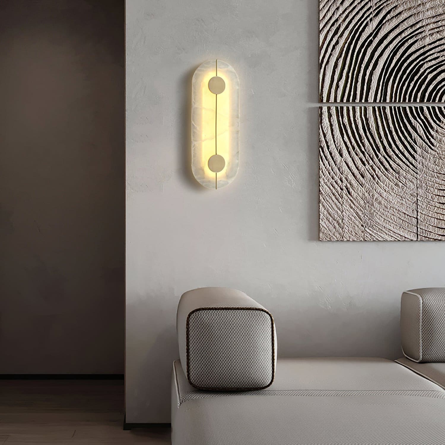 Vertical oval wall light above a sofa beside patterned artwork
