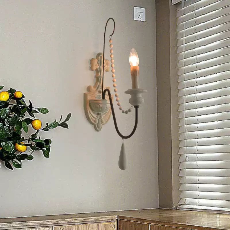 Single-arm candle wall lamp mounted beside a window with blinds