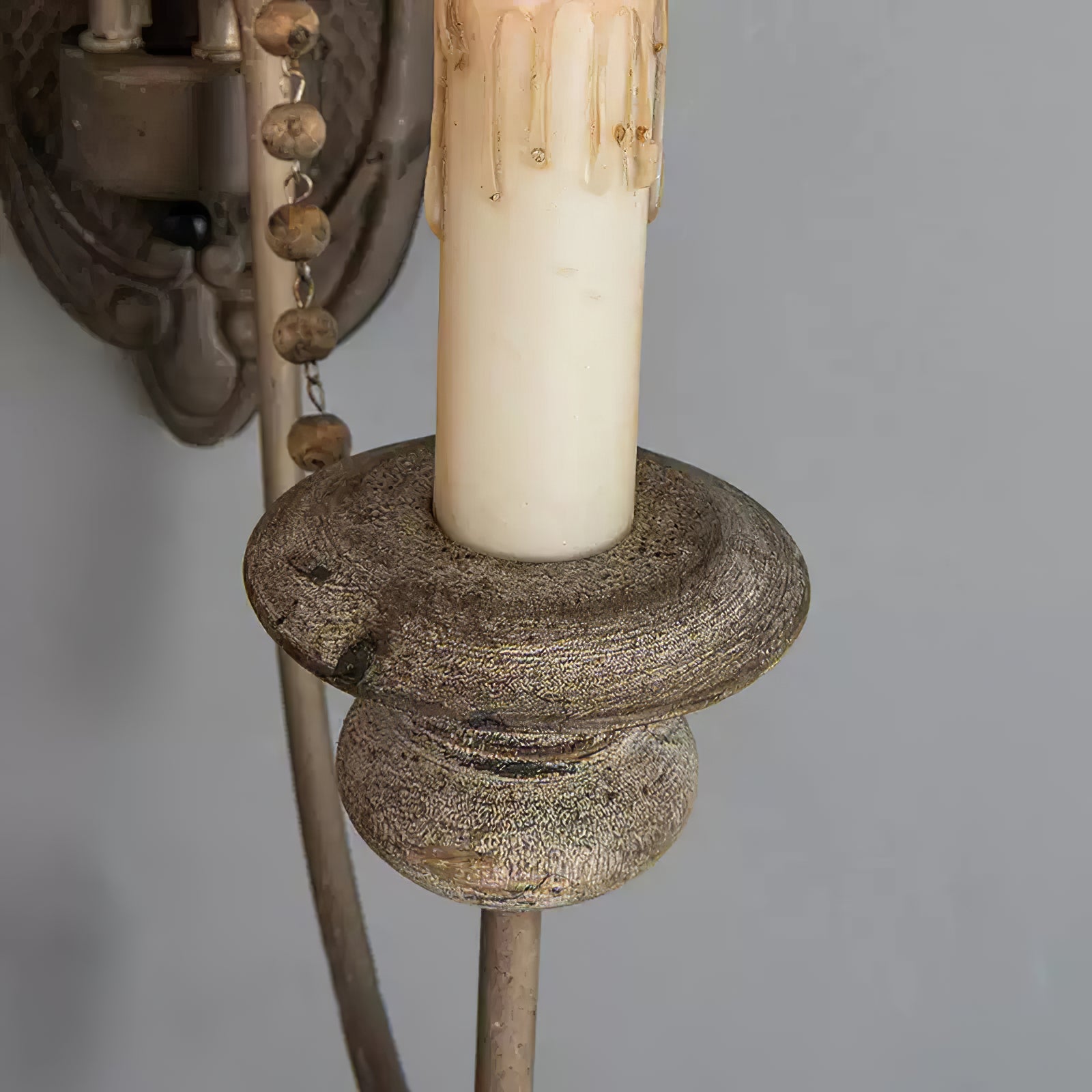 Detail of the candle holder, textured finish and bead strand on the wall lamp