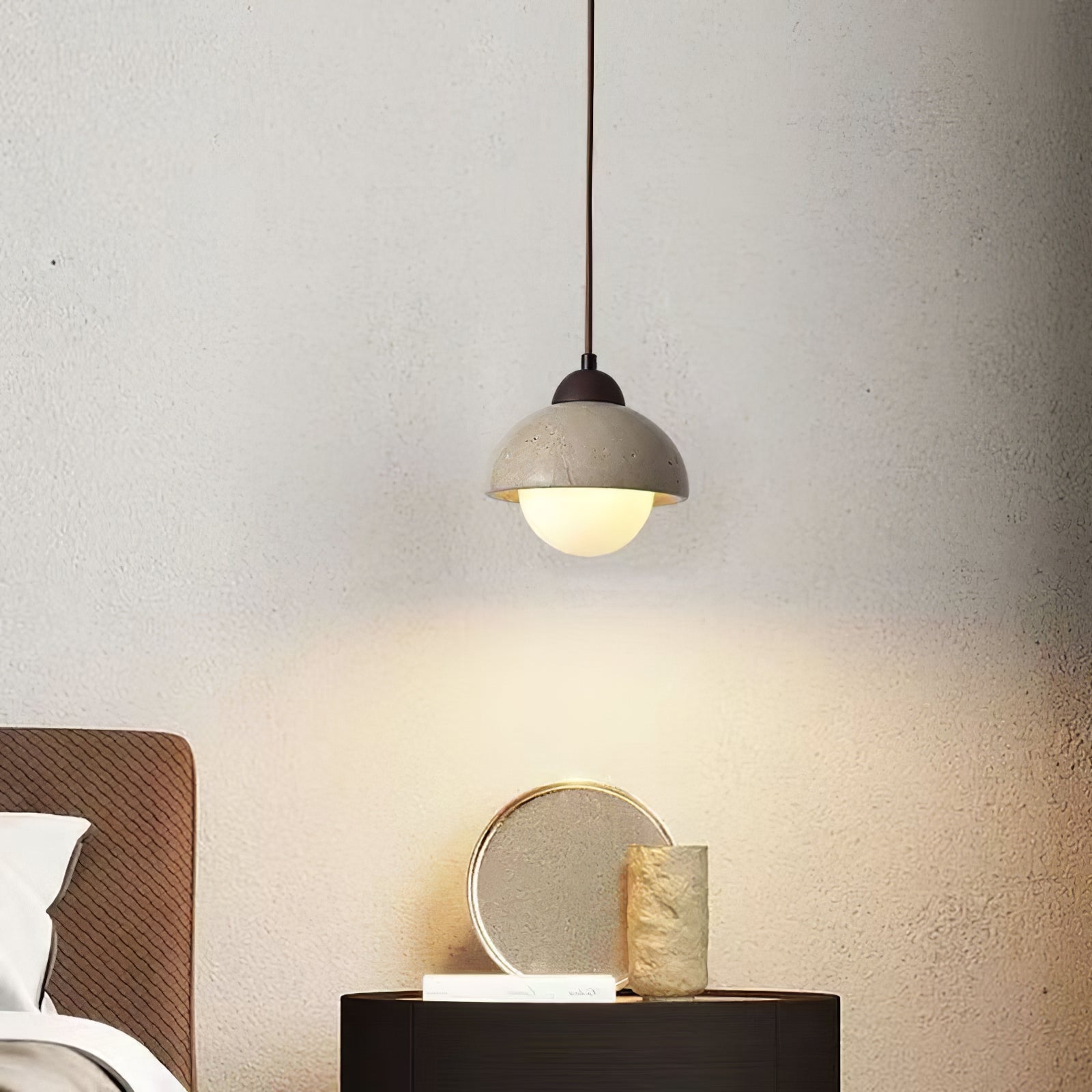 Travertine pendant above a dark cabinet and sculptural vase