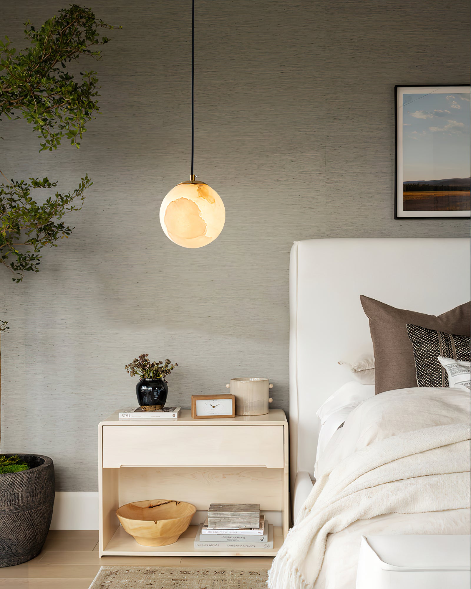 Veined globe pendant above a pale wooden nightstand
