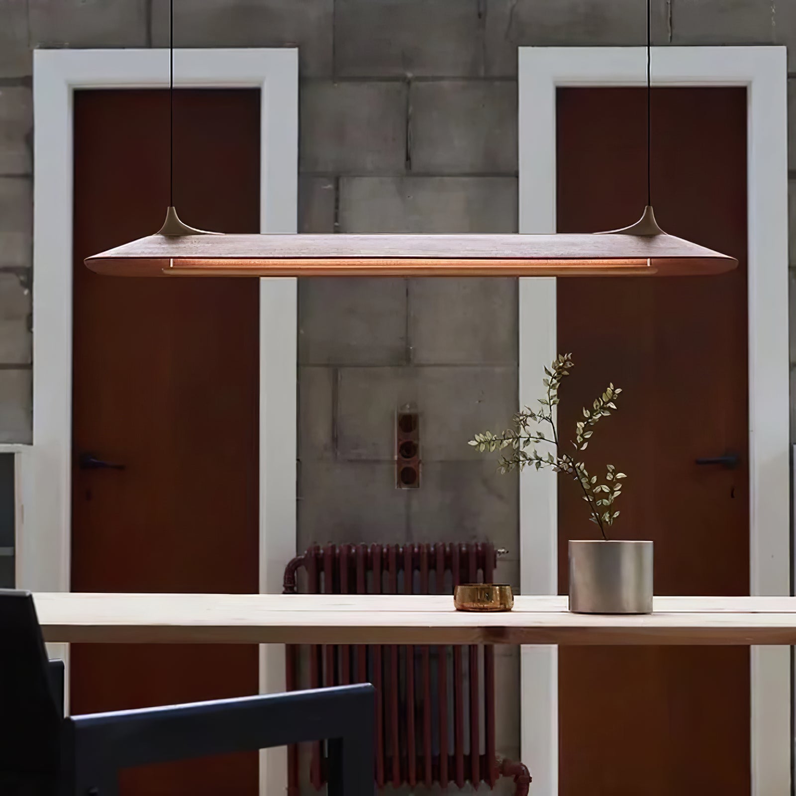 Long wood-finish pendant in front of stone wall panels