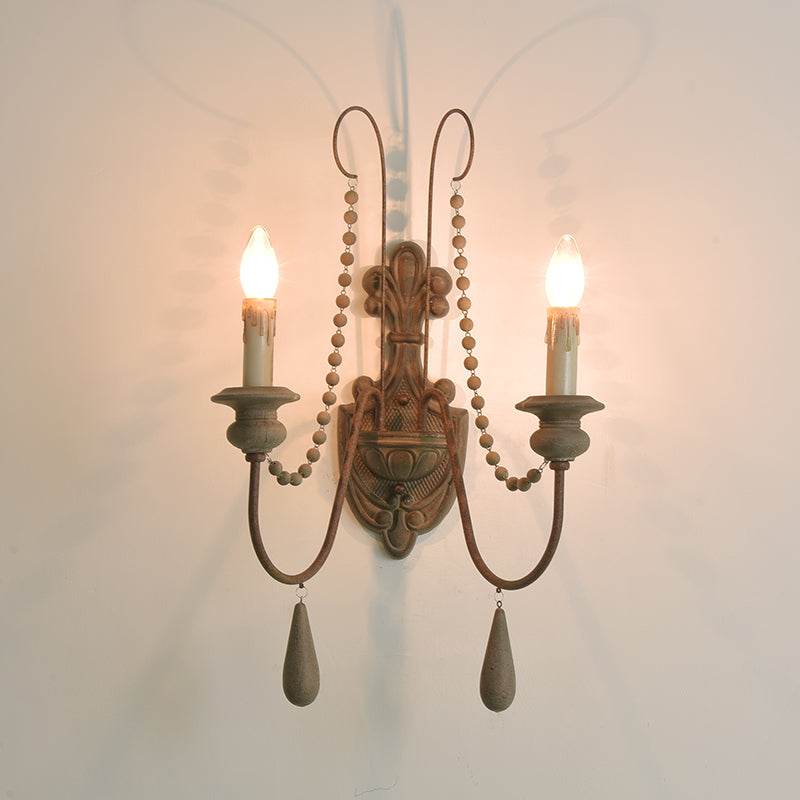 Front view of a lit two-arm country wall sconce with a wood backplate